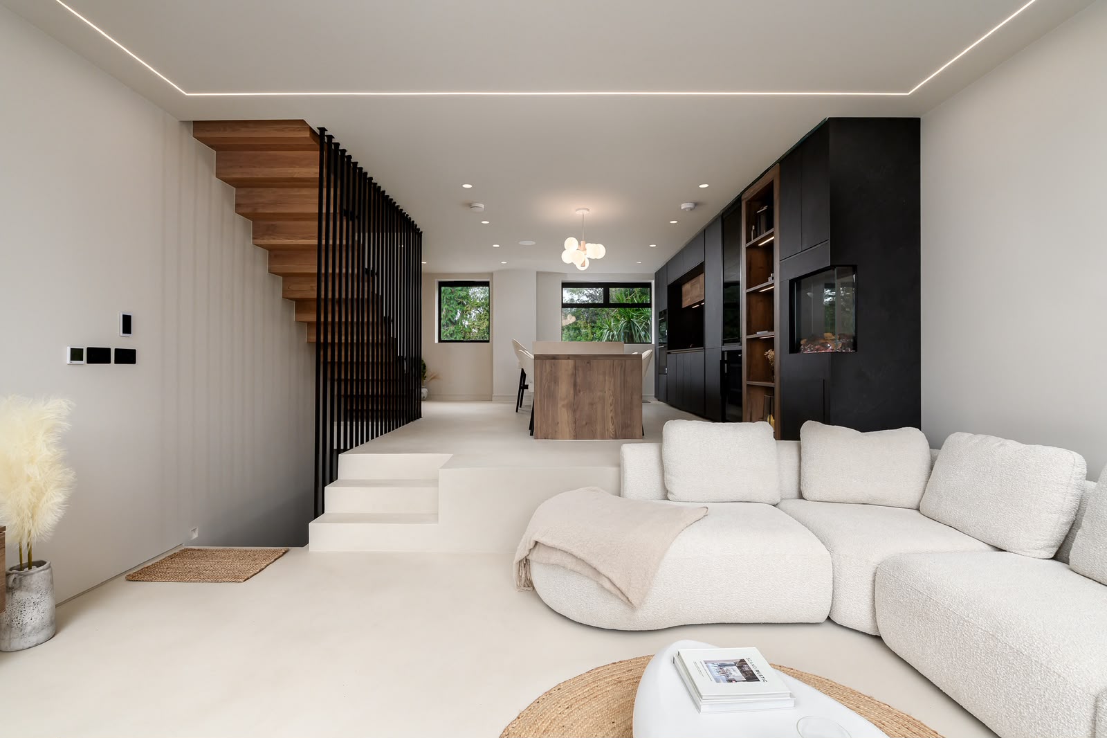 Open-plan living space at Chiswick House, with the kitchen set on a raised level beside a timber staircase