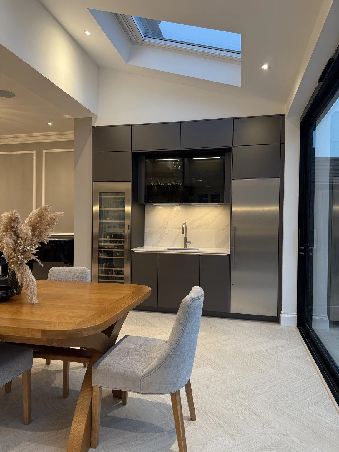 Dedicated bar with full-height wine cooler, stainless-steel fridge, sink and glazed glassware cabinet