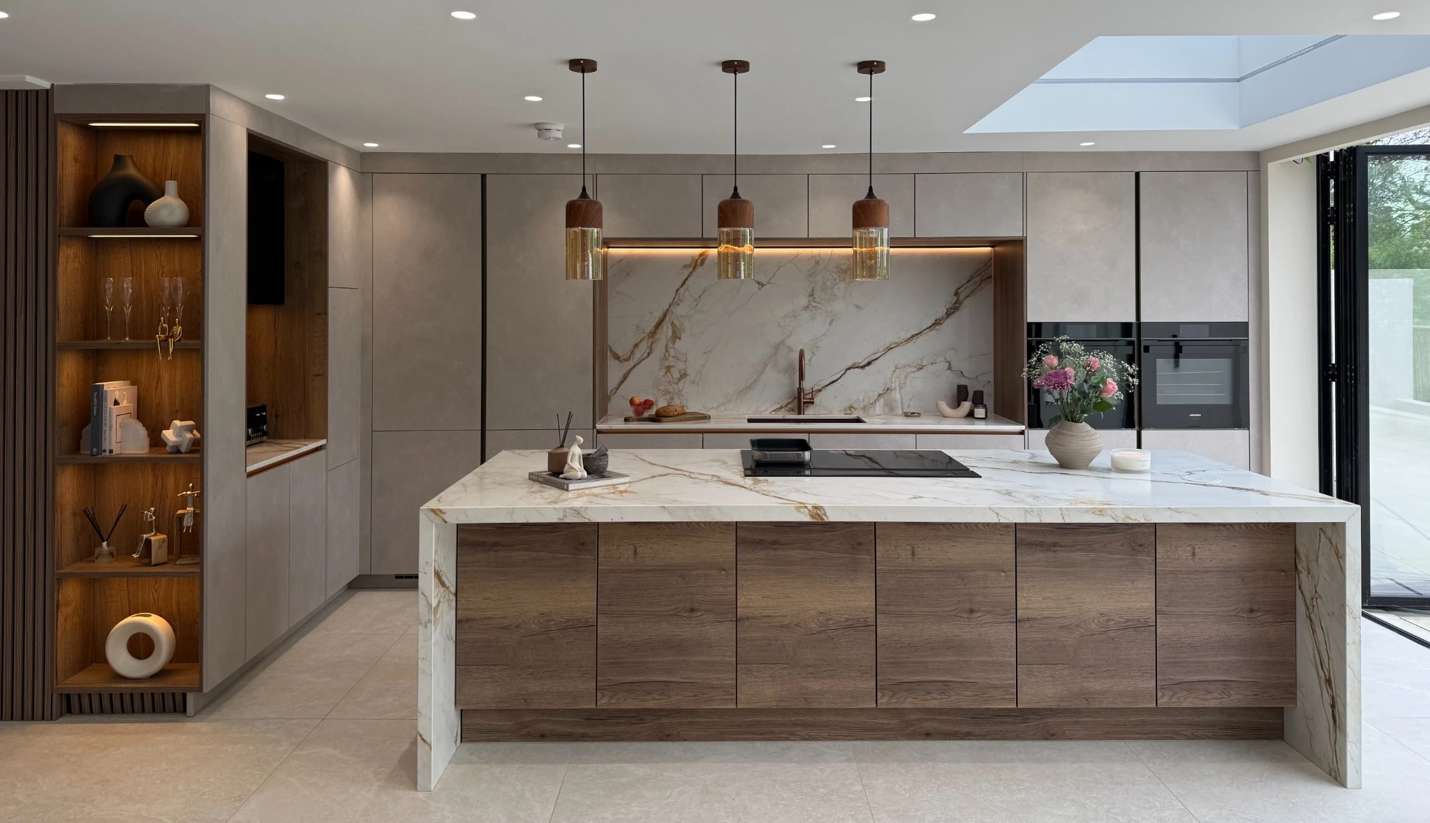 Kitchen with a wide timber island, veined stone worktop and three pendant lights